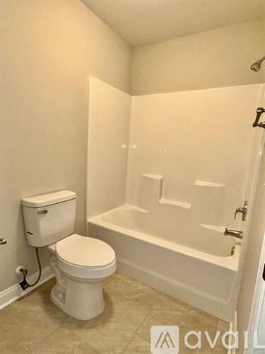 A white toilet and bathtub in a small bathroom.
