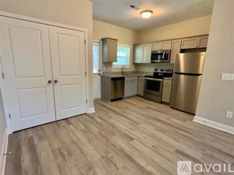A kitchen with white cabinets and a wooden floor.