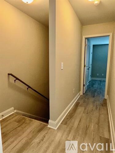 A hallway with wooden floors and a staircase.