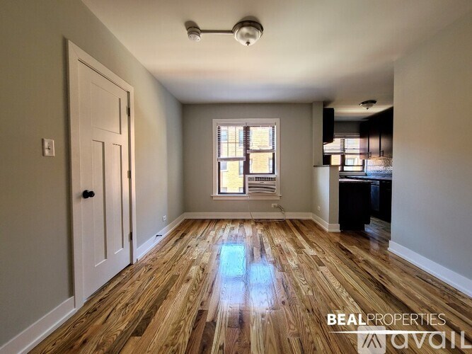 A room with wooden flooring and a window with blinds.