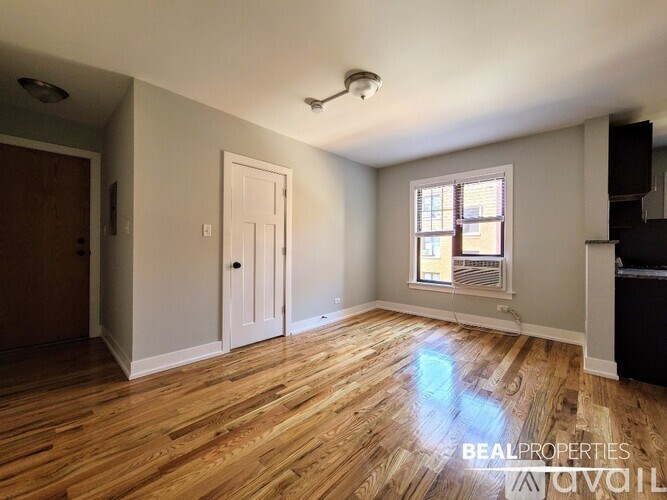 A room with wooden floors and a window with blinds.