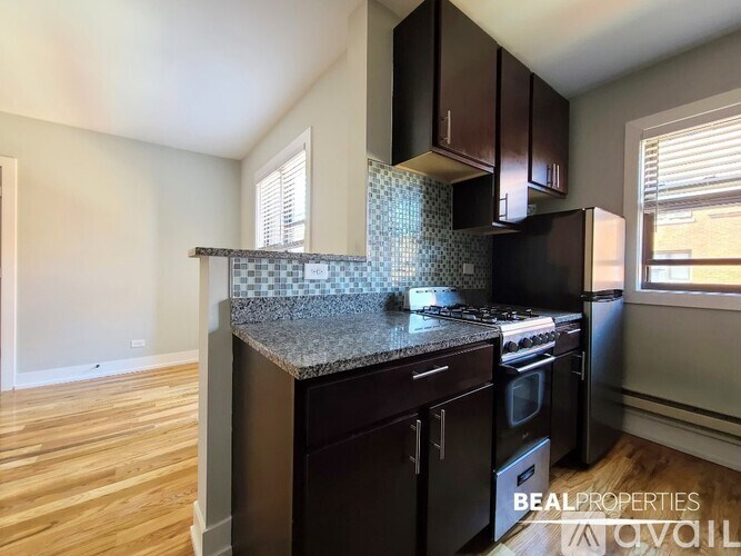 A kitchen with dark wood cabinets and a granite countertop.