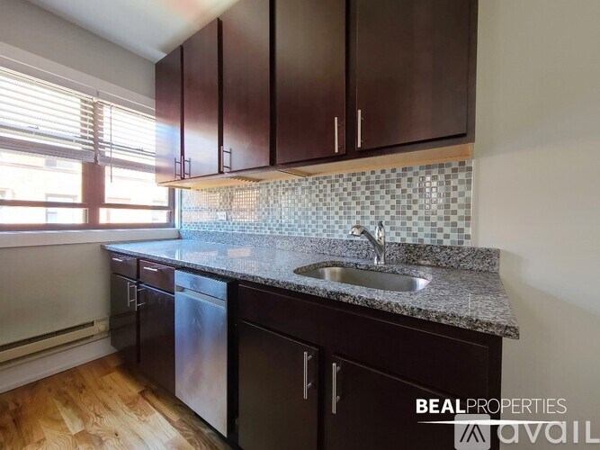 A kitchen with dark brown cabinets and a granite countertop.