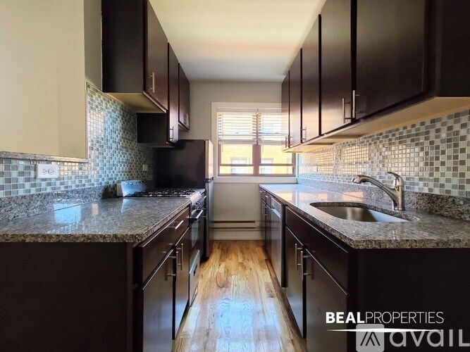A kitchen with dark brown cabinets and a granite countertop.