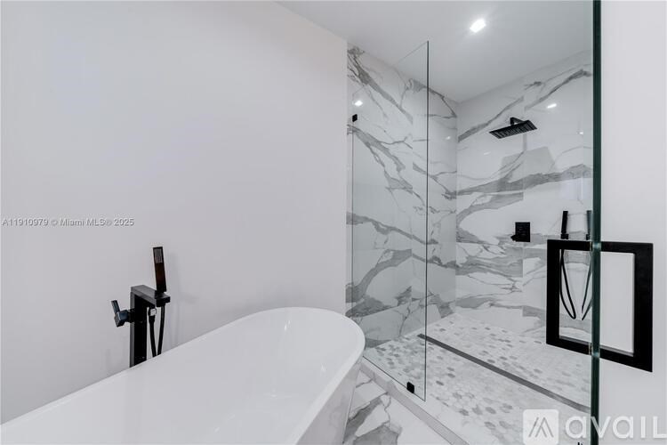 A white bathtub with a glass shower door in a bathroom.