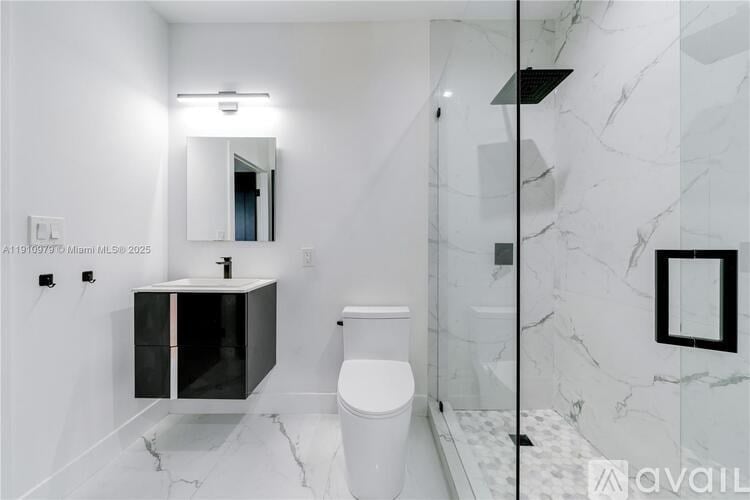 A white toilet sits in a marble bathroom with a mirror and medicine cabinet.
