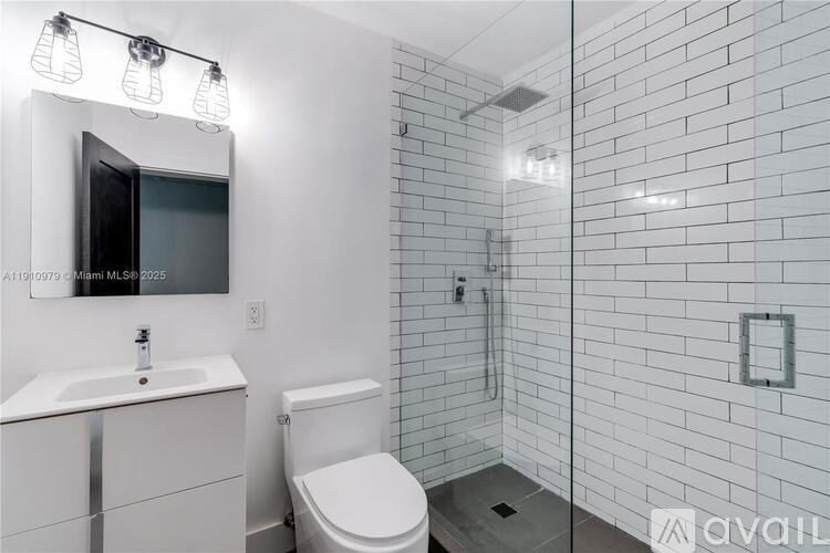 A white bathroom with a toilet, sink, and mirror.