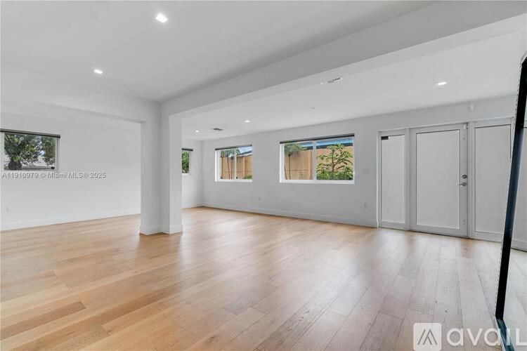 A spacious room with wooden flooring and white walls.