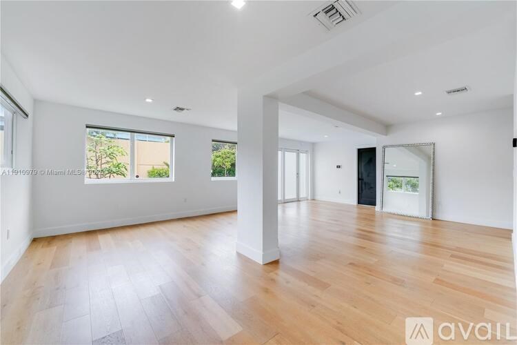 A spacious room with wooden flooring and large windows.