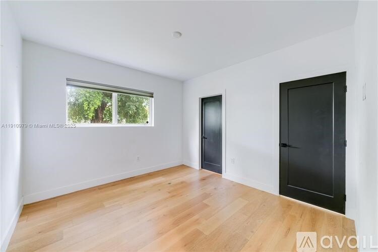 A room with wooden floors and two black doors.