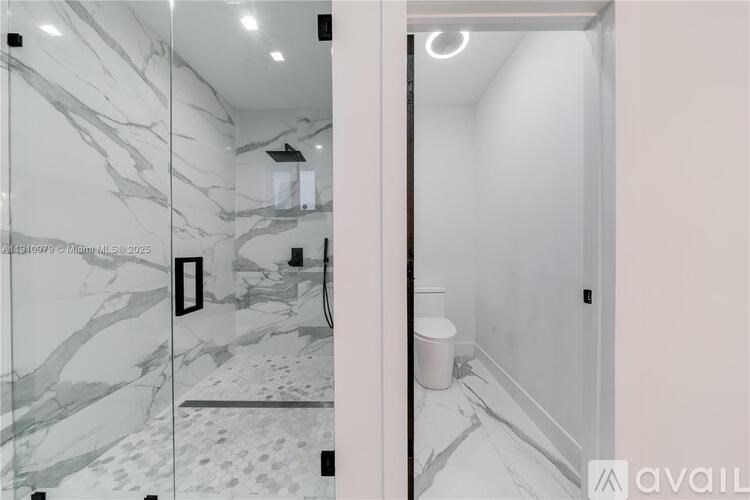 A bathroom with marble tiles on the wall and a toilet in the corner.