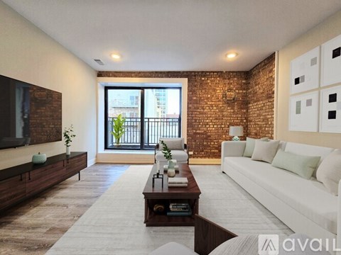 A living room with a white couch, a wooden coffee table, and a brick wall.