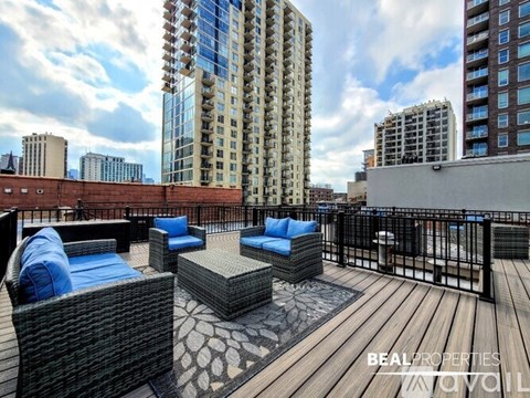 A rooftop patio with wicker furniture and a wooden floor.