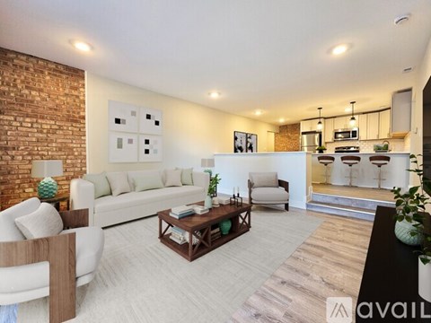 A living room with a white couch, a coffee table, and a brick wall.