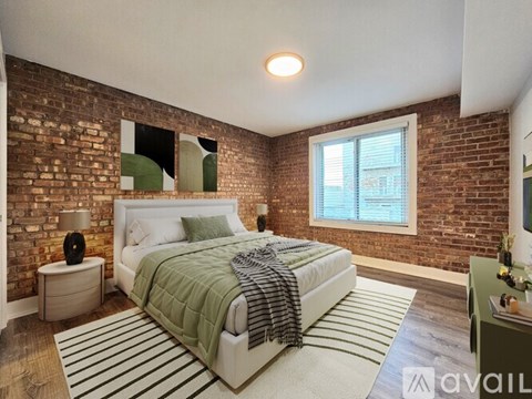 A bedroom with a brick wall and a bed with a green blanket.