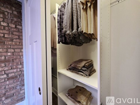 A white closet with a brick wall and a white door.