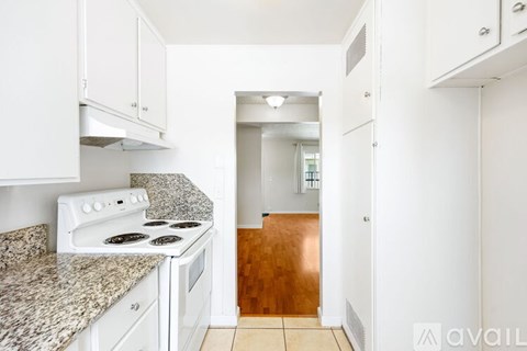 A kitchen with white cabinets and a granite countertop.