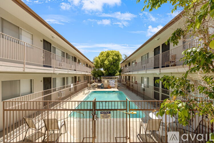A pool in the middle of apartment buildings surrounded by chairs.