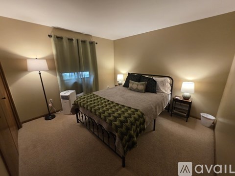 A bedroom with a bed, nightstands, and a window with curtains.