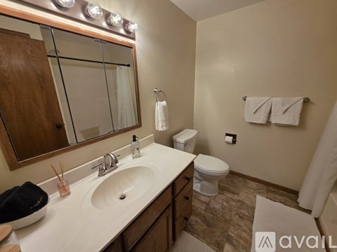 A bathroom with a sink, mirror, toilet, and towels.