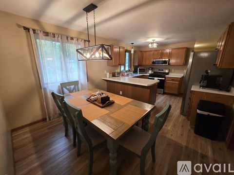 A kitchen with a table and chairs in the foreground and a refrigerator in the background.