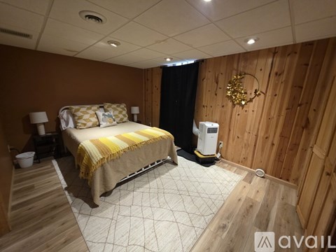 A bedroom with a bed, a lamp, and a wall-mounted fan.