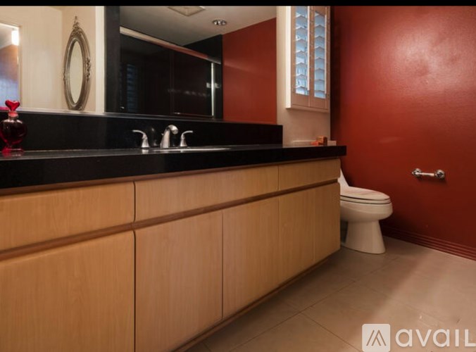 A bathroom with a toilet, sink, and wooden cabinets.