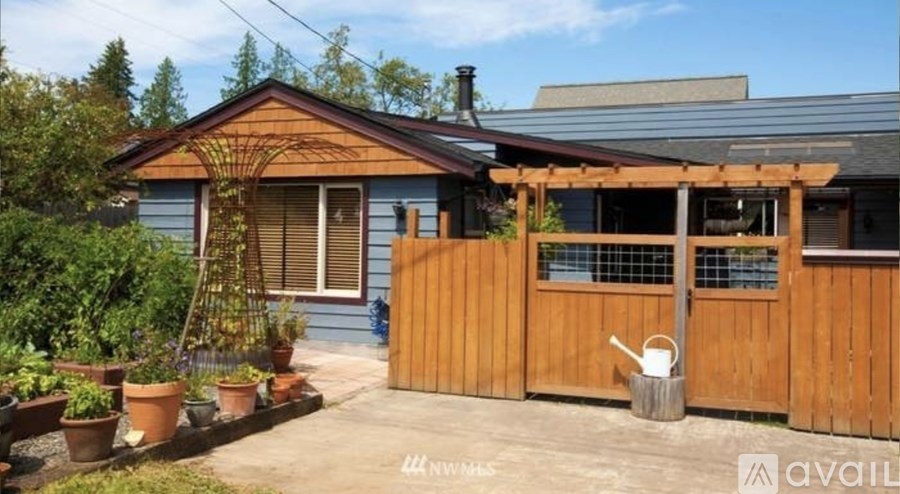 A blue house with a wooden fence and a small garden in front.