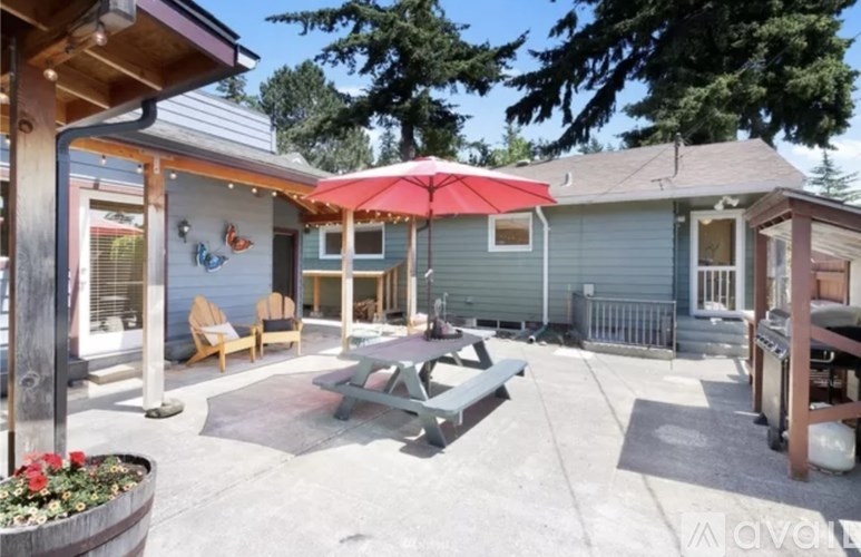 A patio area with a table and chairs and a red umbrella.