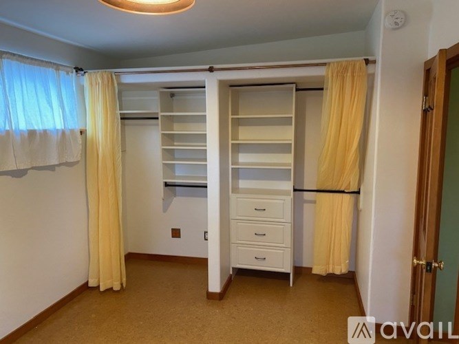 A bedroom with a white wardrobe and yellow curtains.