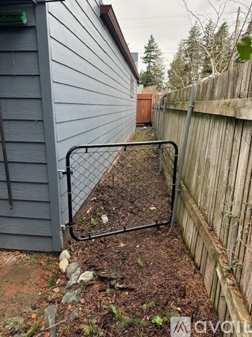 A metal gate is closed to a garden area.