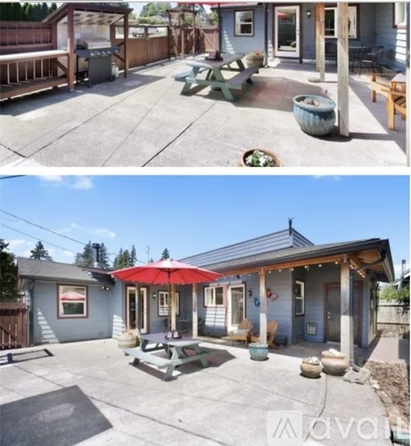 A house with a red umbrella and a patio with a table and chairs.