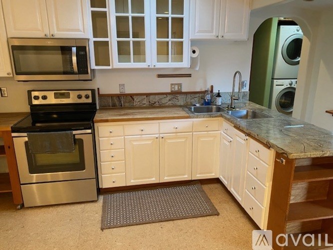 A kitchen with white cabinets and a granite countertop.
