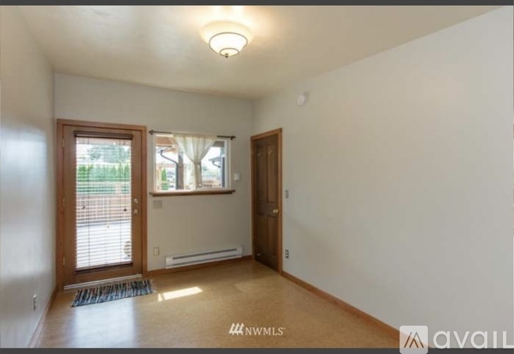 A room with a door, window, and a mat on the floor.