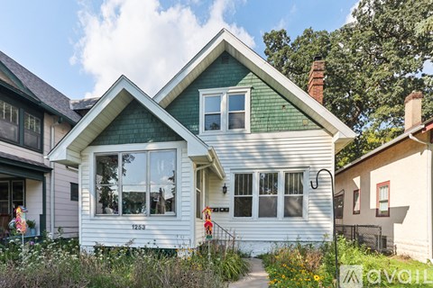 A white house with a green roof is for sale.