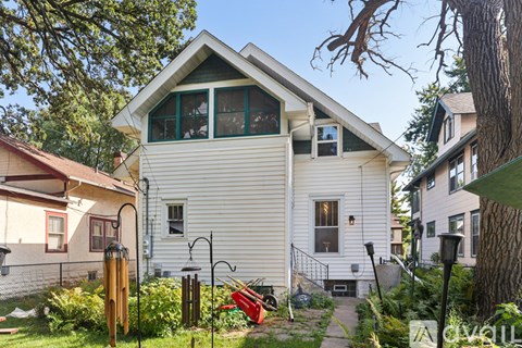 A white house with a red lawn chair in front of it.
