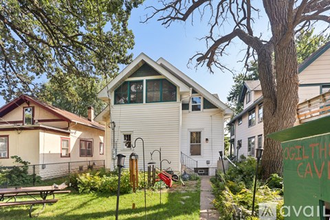 A white house with a green roof is surrounded by trees and has a sign that says "Cavil".
