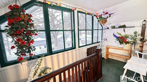 A room with a green window and a hanging flower arrangement.