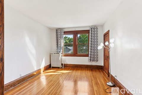 A room with wooden floors and a window with curtains.