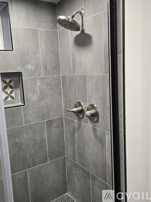 A shower area with a shower head and hand held shower.