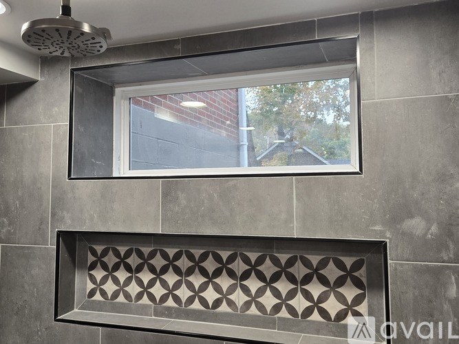 A shower area with a window and a tiled wall.