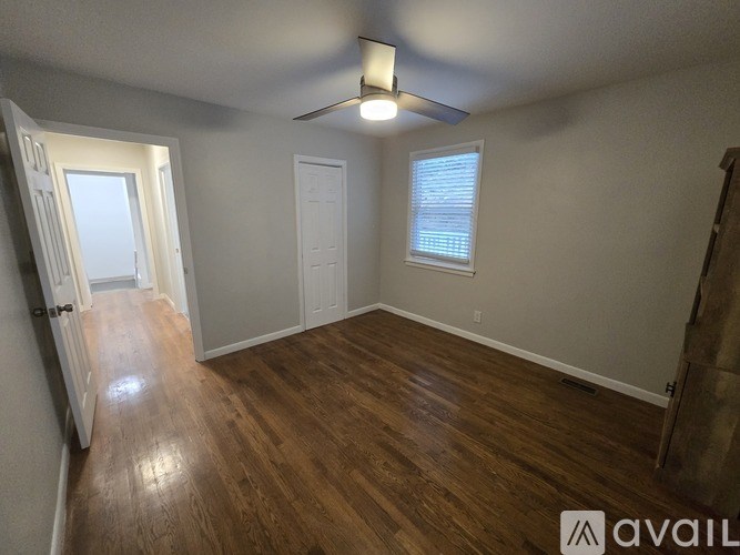 A room with wooden flooring and a window with blinds.