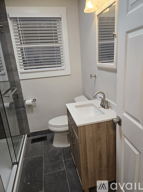 A bathroom with a toilet, sink, and a shower with a glass door.