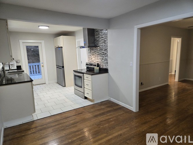 A kitchen with wooden floors and a stone backsplash.