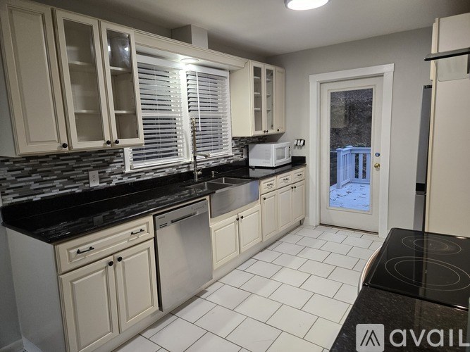 A kitchen with white cabinets and black countertops.