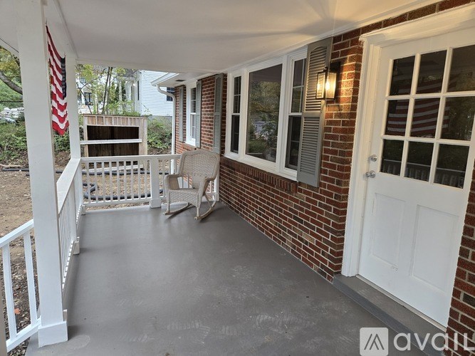 A porch with a white railing and a white door.