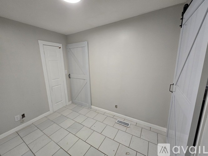 A room with white tile flooring and a white door.