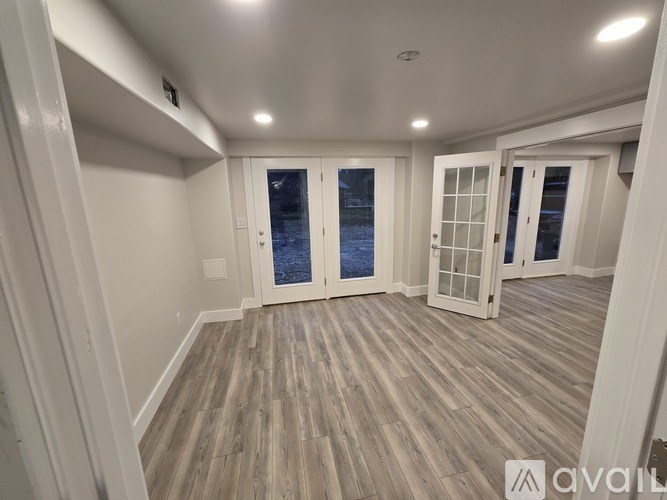 A room with wooden flooring and white walls.
