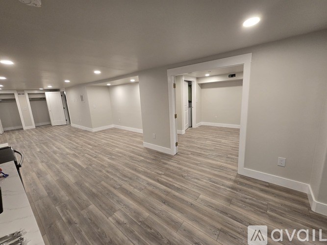 A spacious room with wooden flooring and white walls.