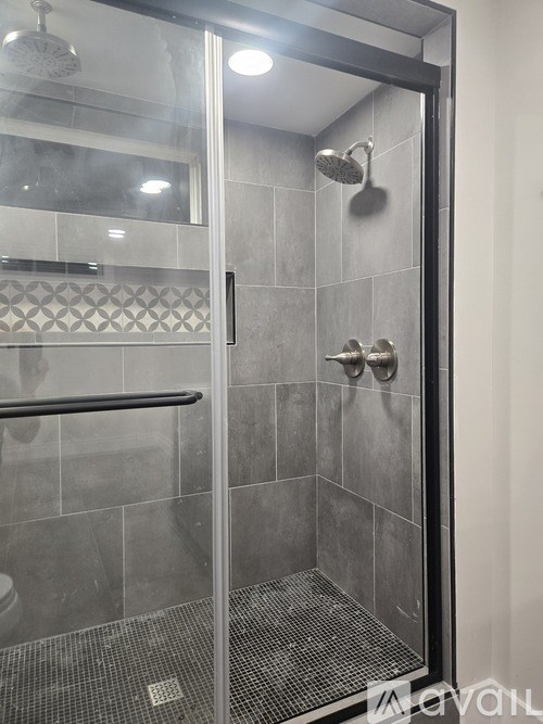 A glass shower door with a handle and a glass window.